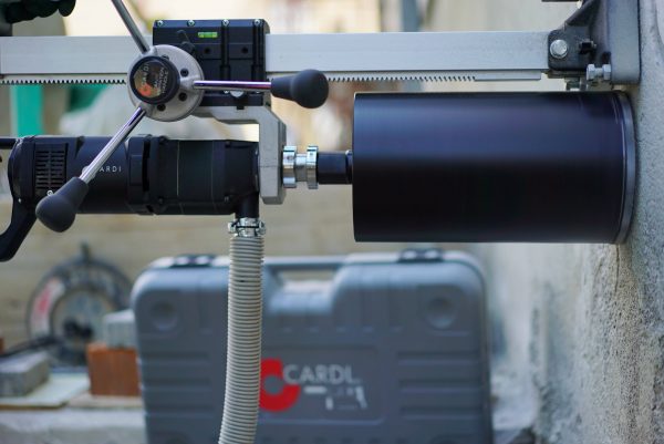 CARDI HS 250 hand-held core drill on stand with DPT micro-percussion technology, drilling a wall.