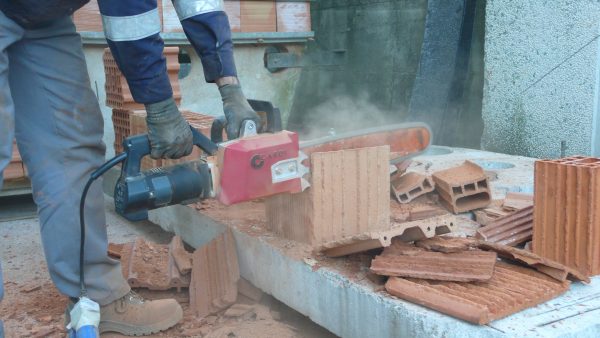 Construction worker cuts a brick using the CARDI AL 22-43 chainsaw.