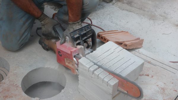 Construction worker cuts a block using the CARDI AL 22-43 chainsaw.