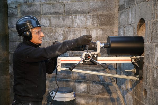 Construction worker drill a wall with CARDI HS-250 core drill on stand.