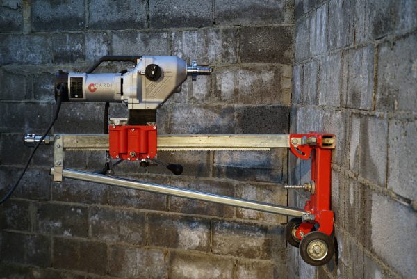Construction worker drill a wall with CARDI 500 core drill on stand.